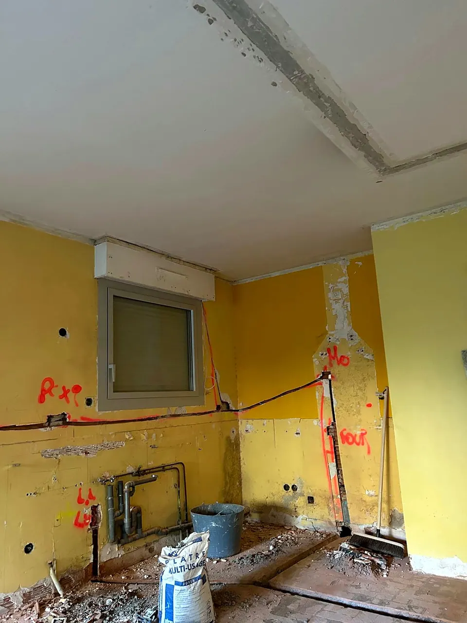 Saignées et repères tracés au mur pendant une mise aux normes